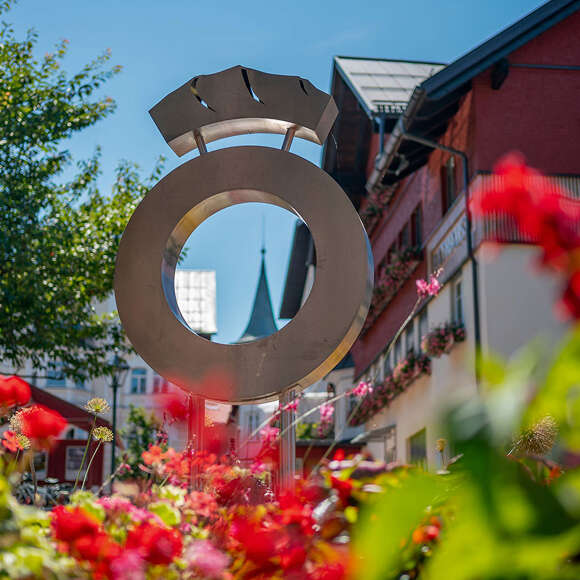 Oberstaufen Logo vor dem Rathaus im blühenden Blumenbeet