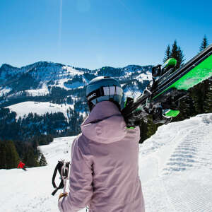 Frau mit geschulterten Ski in der Skiarena Steibis.