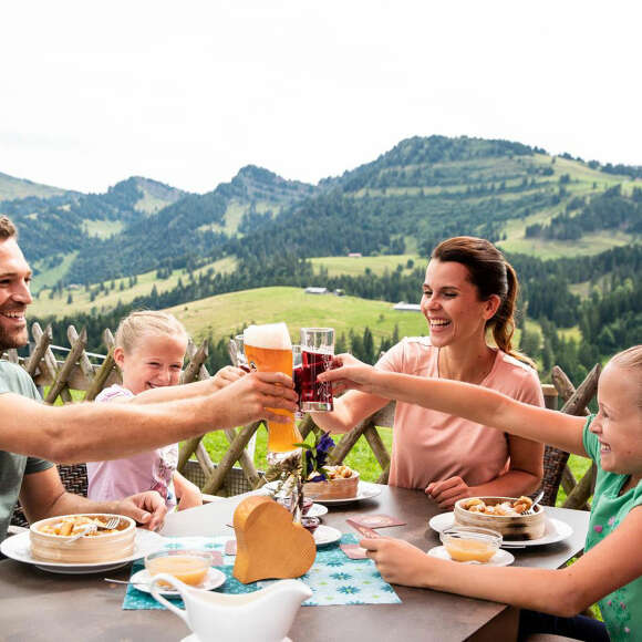 Familie bei der Einkehr auf einer Hütte im Imberggebiet mit Blick auf die Berge.