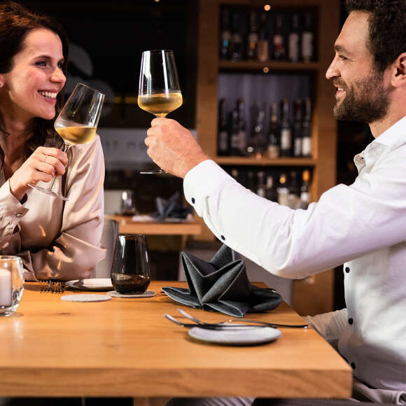 Paar stößt in einem Restaurant mit Weißwein an.