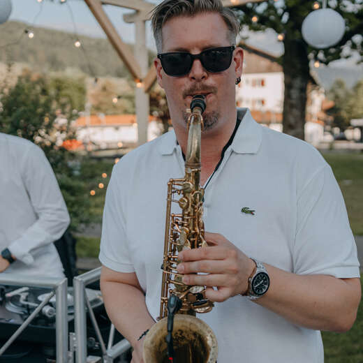 Mann in weißem T-shirt spielt Saxophon im Oberstaufen PARK.