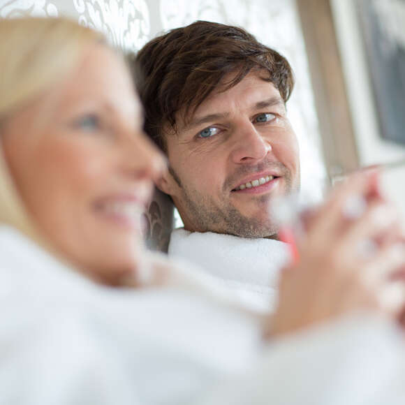 Mann und Frau liegen im Bett. Mann blickt sie an.