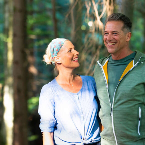 Mann und Frau im sportlichen Outfit im Wald.