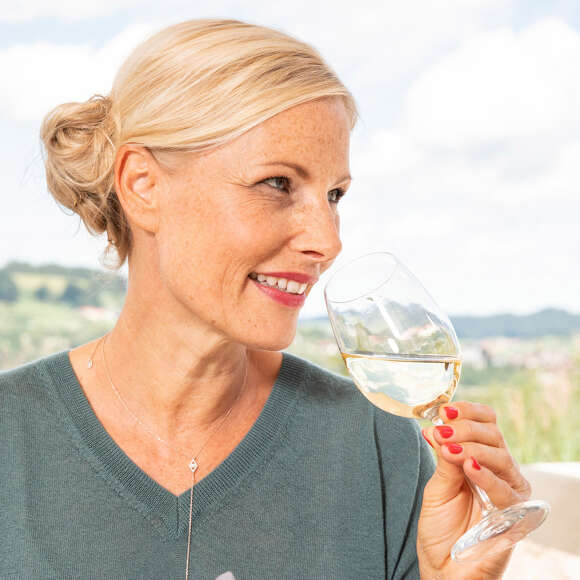 Frau nimmt einen Schluck Weißwein aus einem Weinglas.