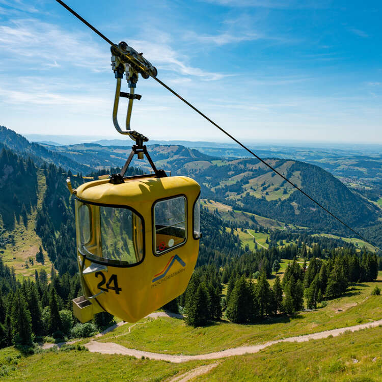 Blick auf die gelbe Gondel der Hochgratbahn mit Bergpanorama im Sommer.
