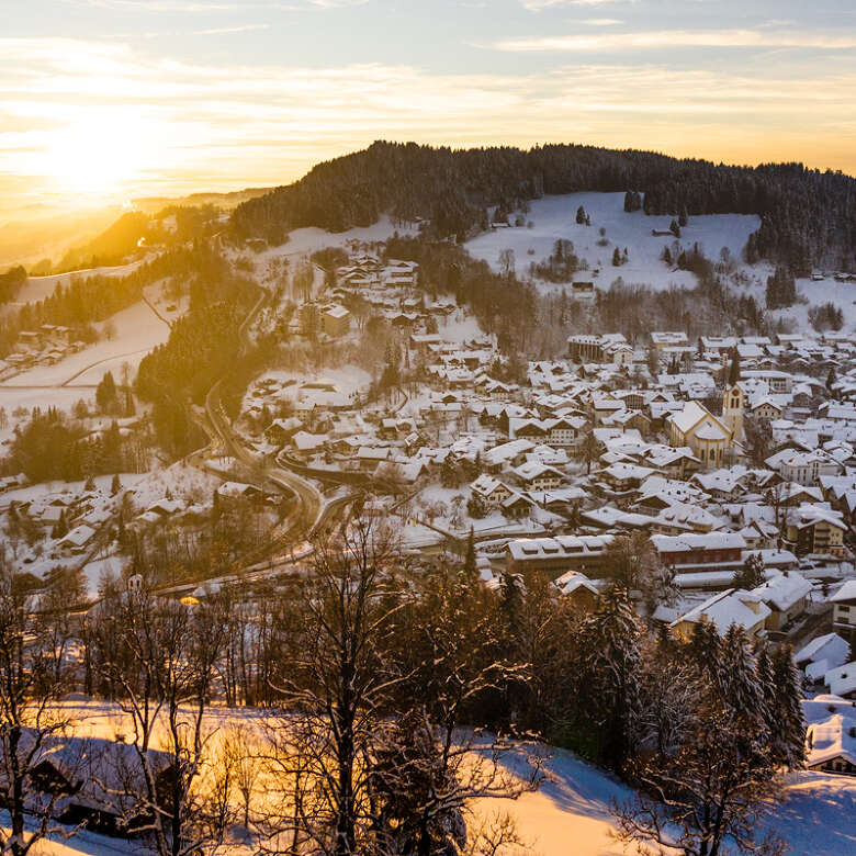 Sonnenuntergang über den verschneiten Dächern von Oberstaufen.