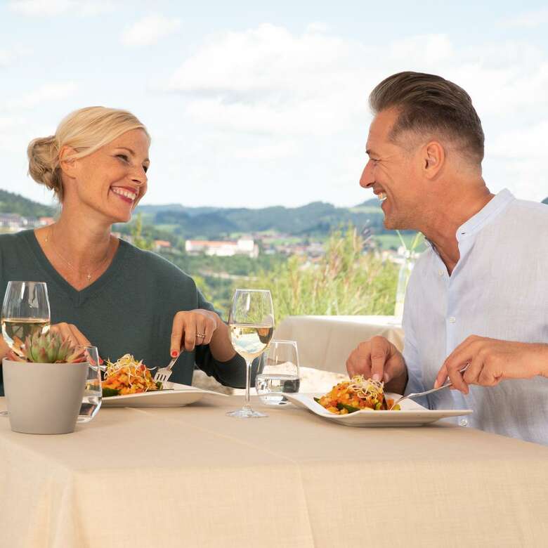 Paar beim Essen auf der Terrasse eines Restaurants mit Blick auf Oberstaufen.