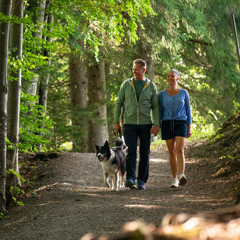 Paar mit ihrem Hund auf einem Wanderweg bei Oberstaufen.