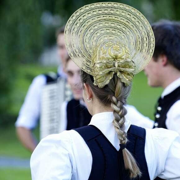 Rückansicht einer Frau der Volkstanzgruppe in traditioneller Tracht und Radhaube.