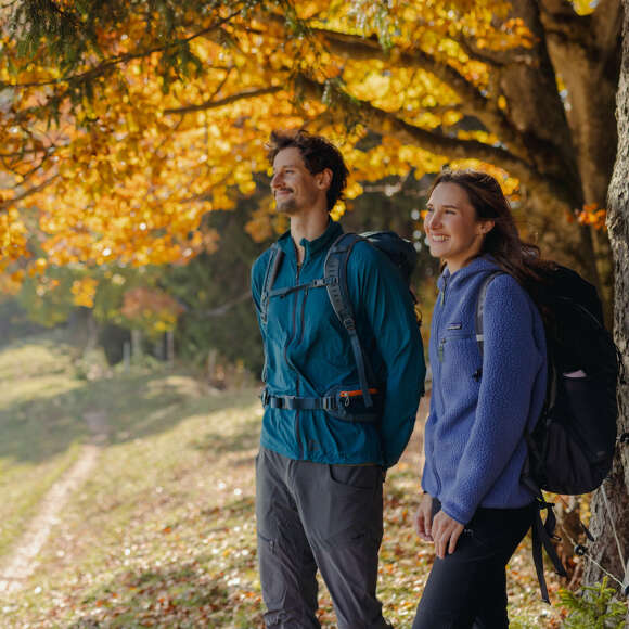 Wanderer am Kojenstein Zwei Wanderer stehen unter goldgelb gefärbten Bäumen auf dem Waldweg am Kojenstein in Oberstaufen im Allgäu.