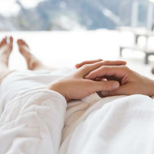 Person im Bademantel mit Ausblick in die Berge.