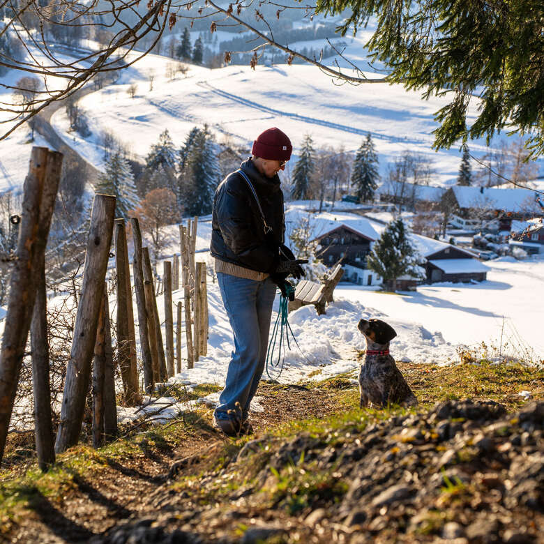 Gassi gehen mit Bergpanorama Ein Hund sitzt an der Leine vor seinem Herrchen.