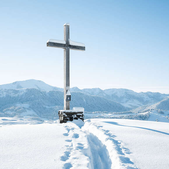 Gipfelkreuz der Salmaser Höhe im Winter mit Ausblick auf die Nagelfluhkette.