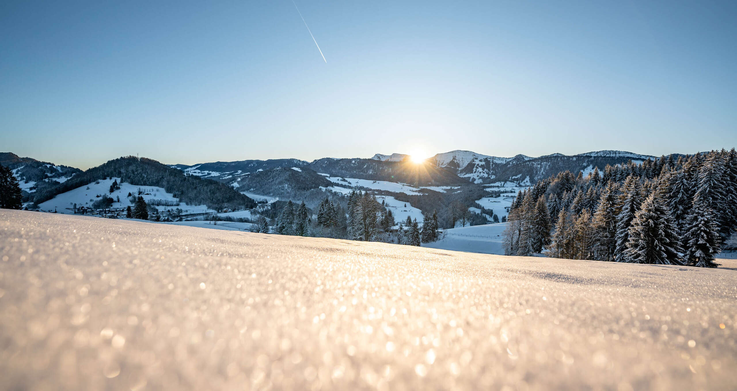Glitzernde Schneelandschaft mit Bergpanorama von Oberstaufen in der Wintersonne.