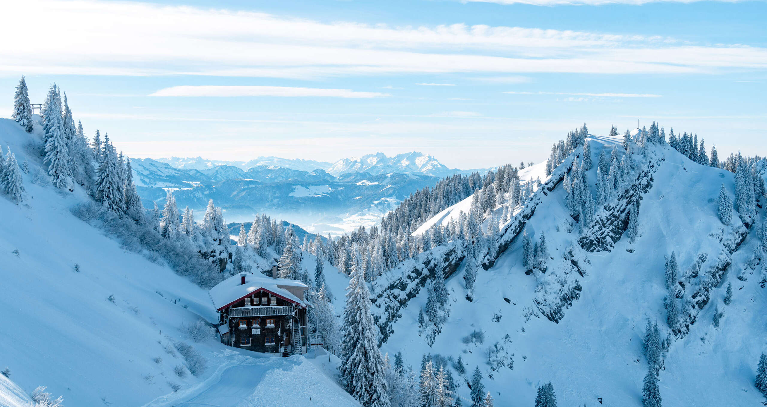 Das Staufner Haus in den verschneiten Bergen mit Panorama der Allgäuer Alpen.