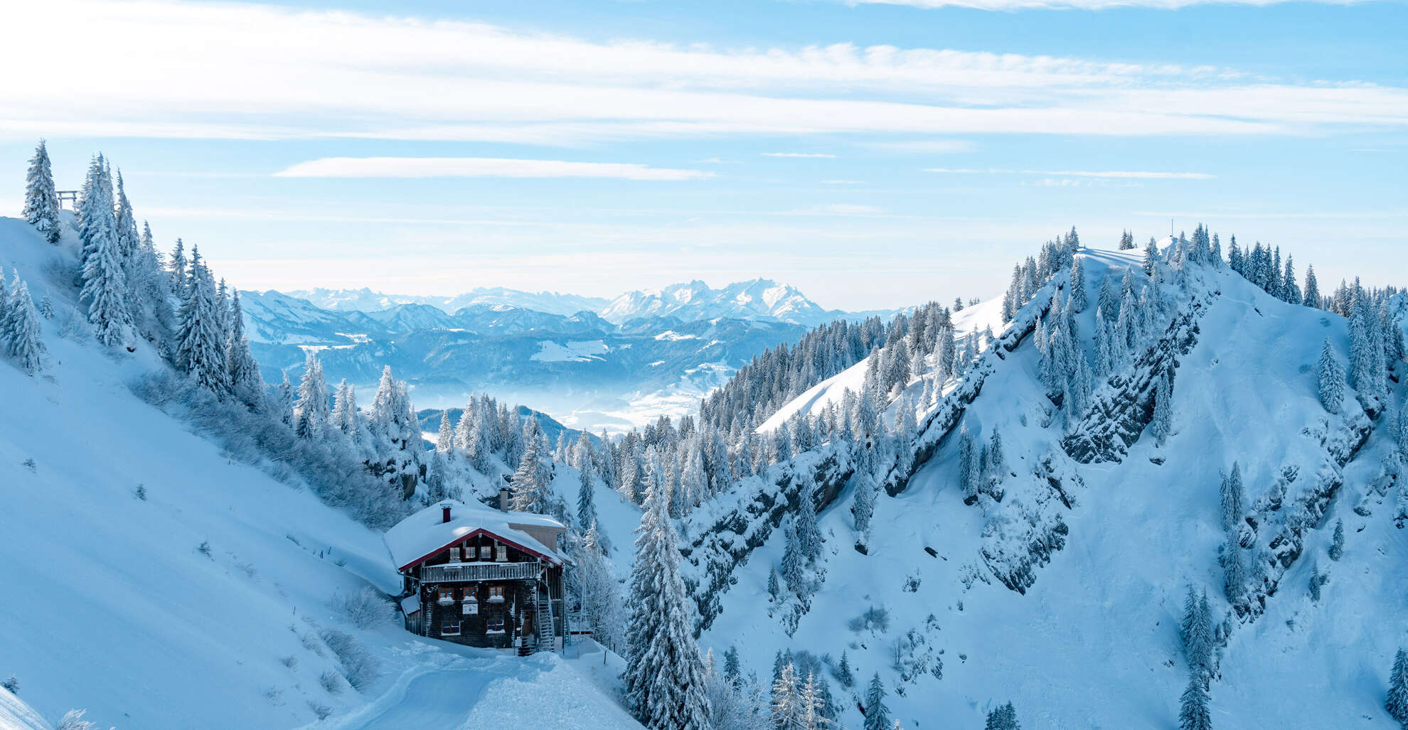 Das Staufner Haus in den verschneiten Bergen mit Panorama der Allgäuer Alpen.