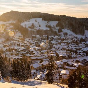 Blick auf das verschneite Ortszentrum von Oberstaufen in der untergehenden Wintersonne.
