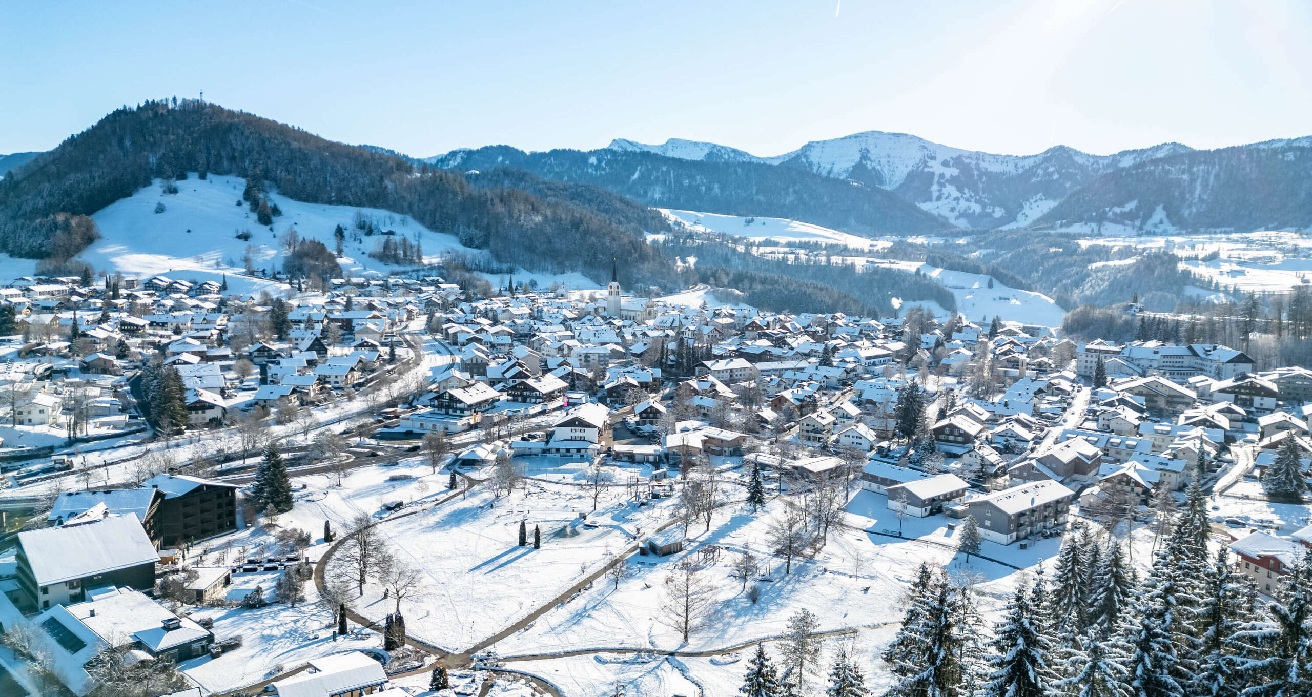 Ortspanorama von Oberstaufen mit Ausblick auf den Hochgrat und die Berge.