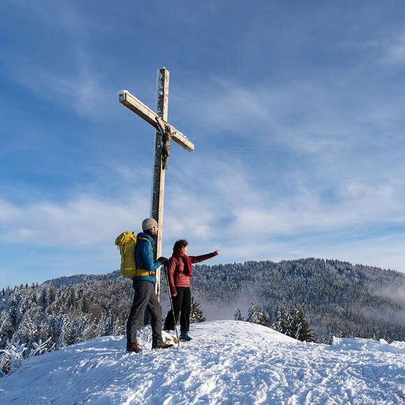 Wanderer am verschneiten Gipfel der Juget-Höhe bei Oberstaufen mit Bergpanorama