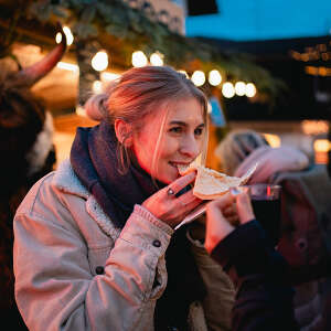Frau isst Crepe auf dem Wintermarkt im Allgäu