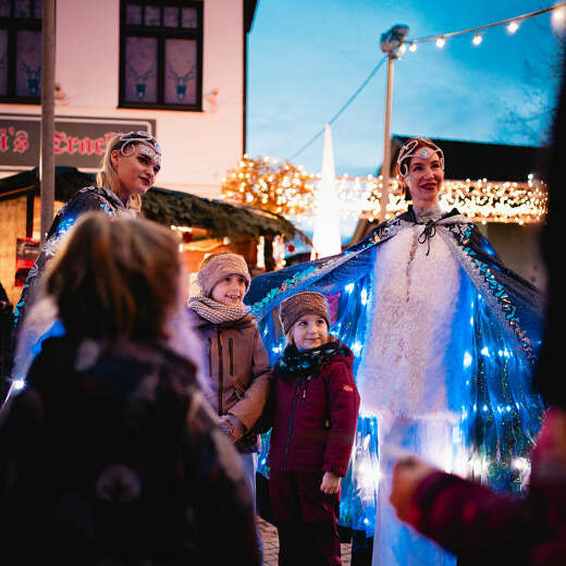 Kinder machen ein Foto mit den leuchtenden Walking Acts des Winterzauber in Oberstaufen