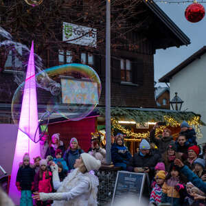Winterzauber große Seifenblase Große Seifenblase vor pinkleuchtendem Eiszapfen und Publikum mit Blick auf Hütte
